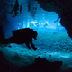 Un buceador explora las partes más inaccesibles del gran Cenote de Sac Actun, con un grupo de turistas al fondo.